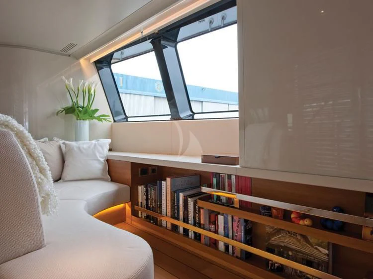 a living room with a white couch and a large window aboard PANTHALASSA Yacht for Sale