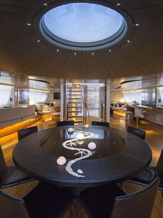 a room with a round table and chairs and a large window aboard PANTHALASSA Yacht for Sale