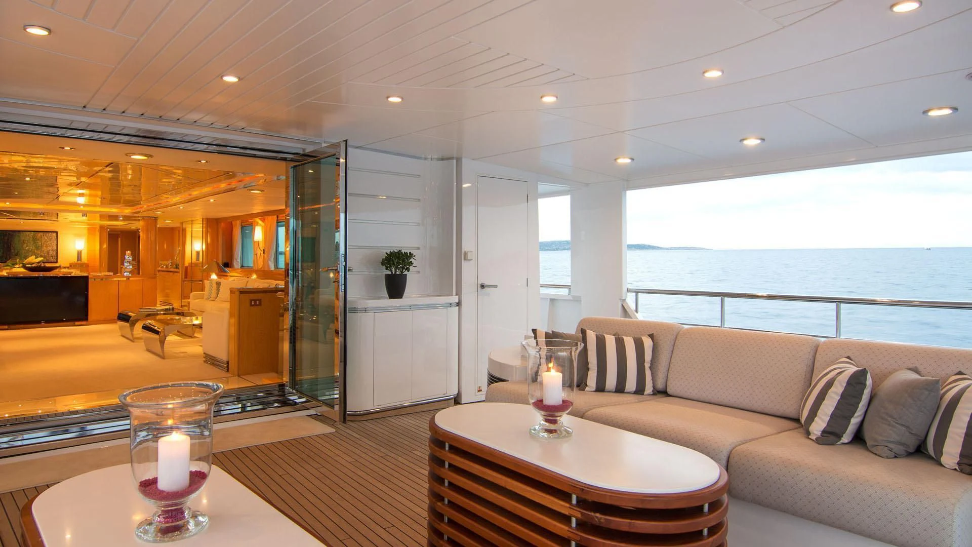 a living room with a large glass door and a table with candles on it aboard O'NATALINA Yacht for Sale