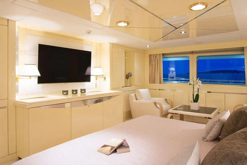 a large white bedroom with a large flat screen tv and a white couch aboard O'NATALINA Yacht for Sale