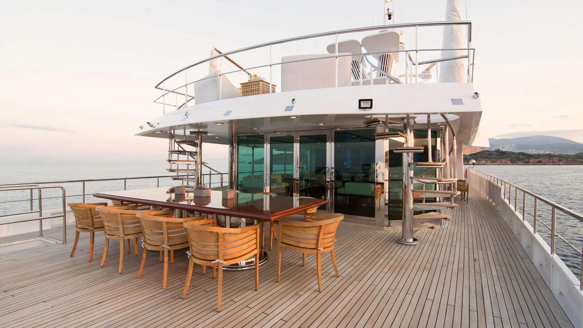 a deck with tables and chairs on it by the water aboard O'NATALINA Yacht for Sale