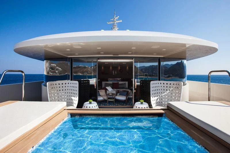 a swimming pool with chairs and a table and chairs aboard SARAMOUR Yacht for Sale