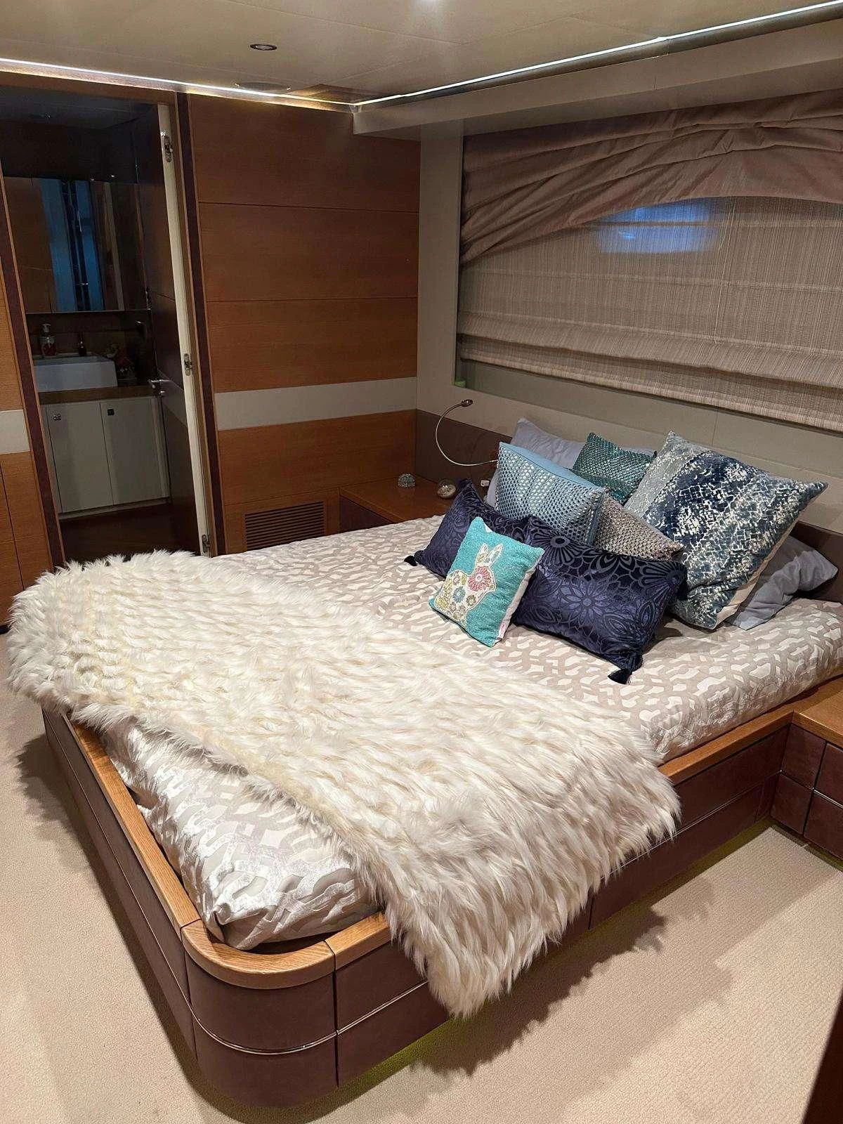 a bed with a white sheet and blue pillows aboard KIMBERLIE Yacht for Sale