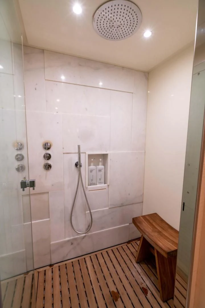 a shower with a sink and a wooden bench aboard PHOENIX Yacht for Sale