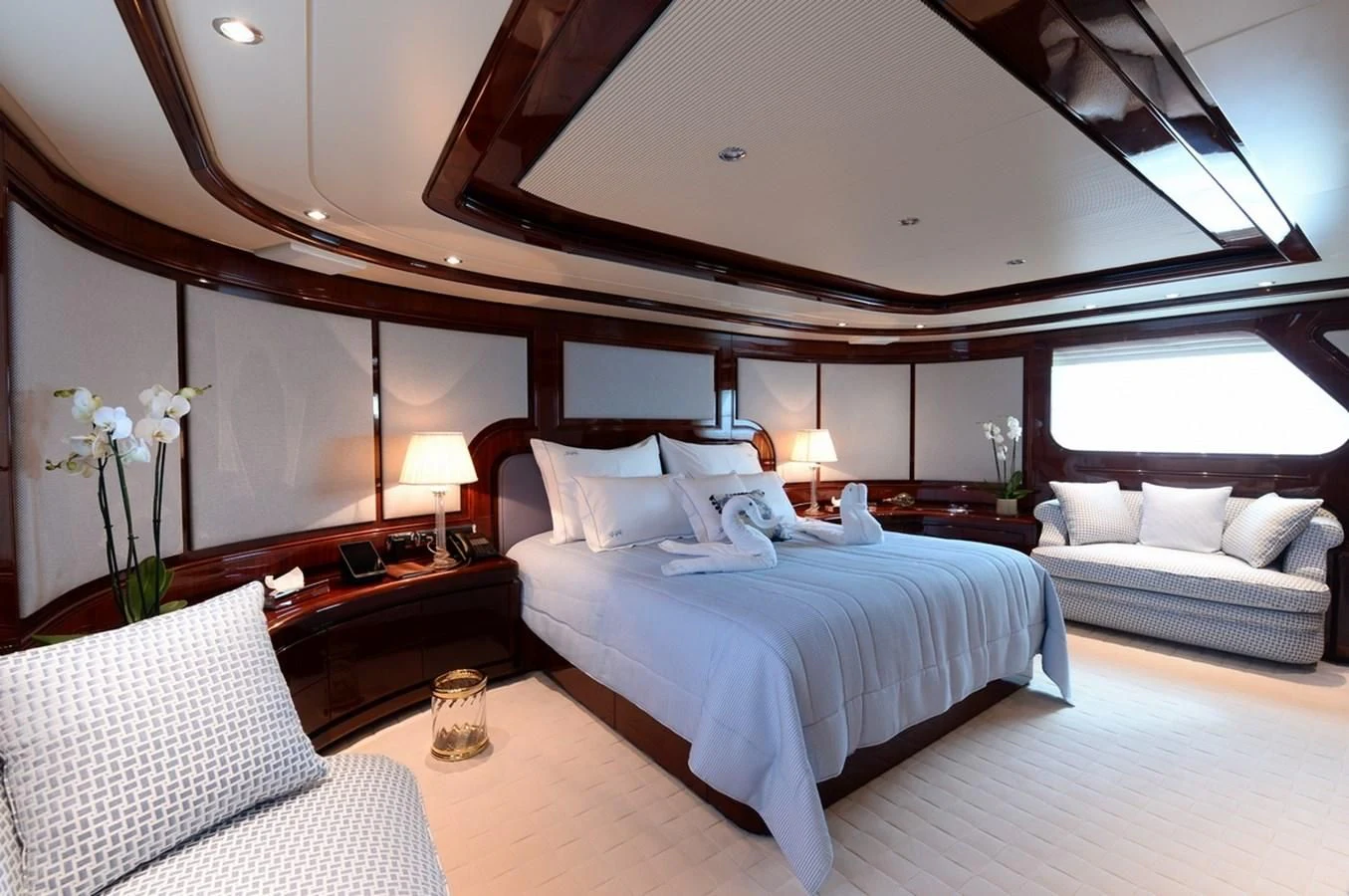 a room with a bed and a table with a glass of wine aboard SUITE Yacht for Sale