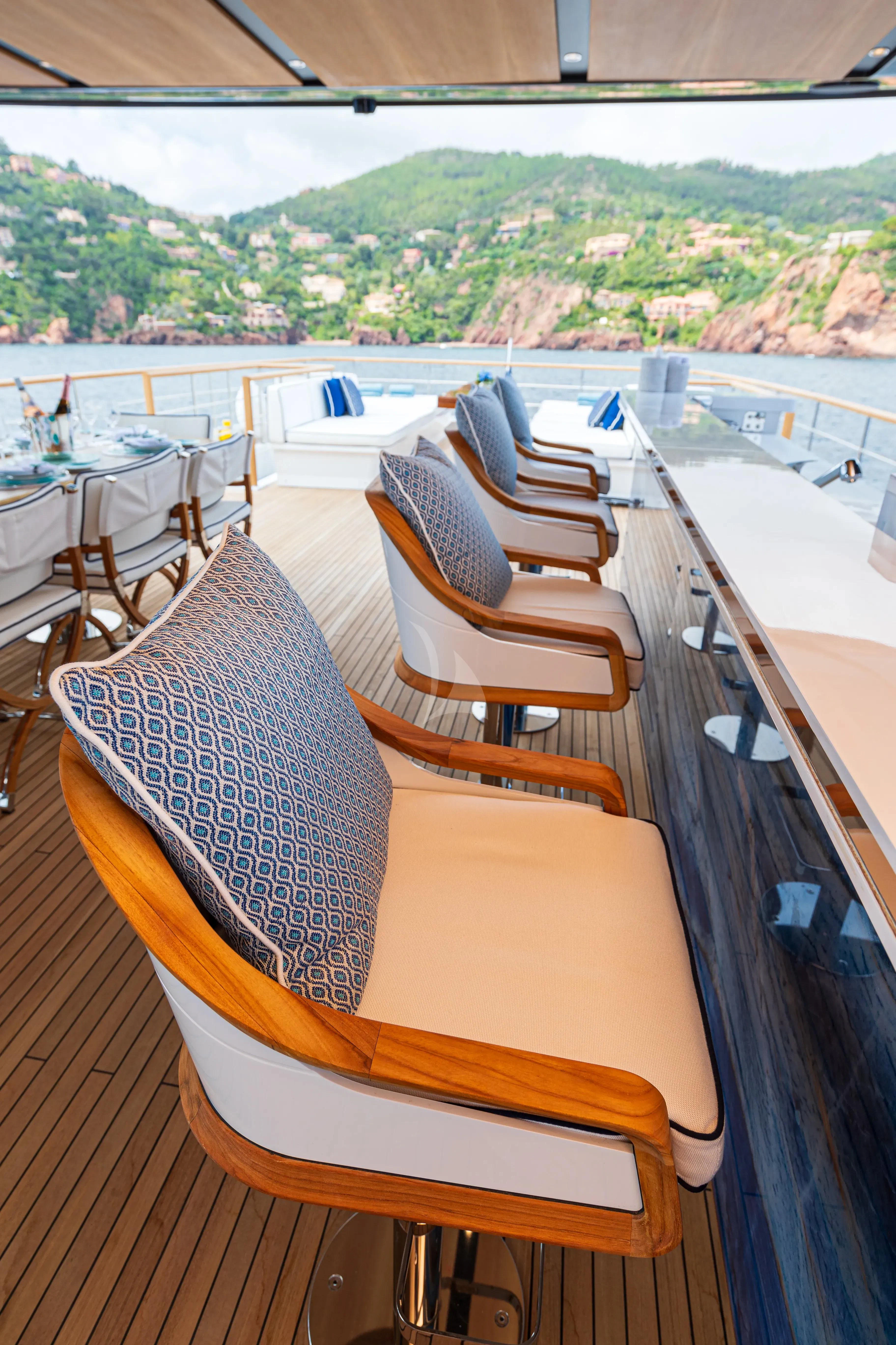 a deck with chairs and a body of water and trees in the background aboard LAFAYETTE Yacht for Sale