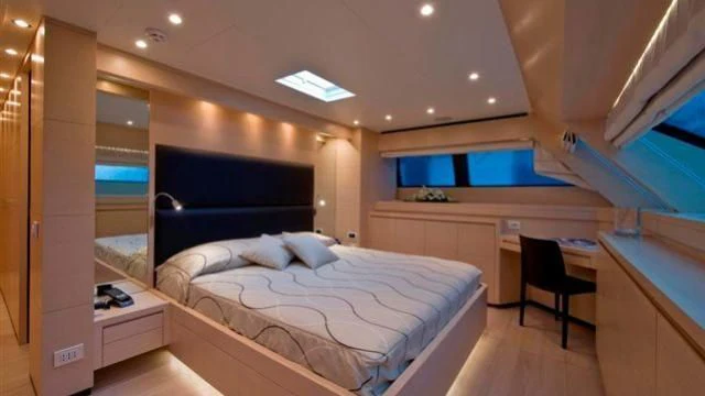 a room with a bed and desk aboard ELYSIUM Yacht for Sale