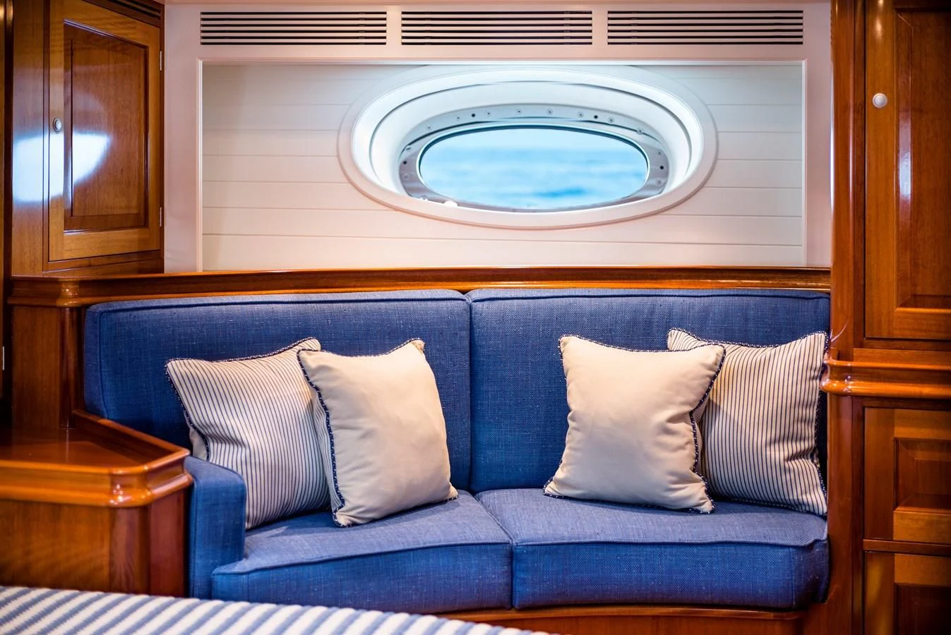 a couch with pillows and a round window above it aboard ATALANTE Yacht for Sale