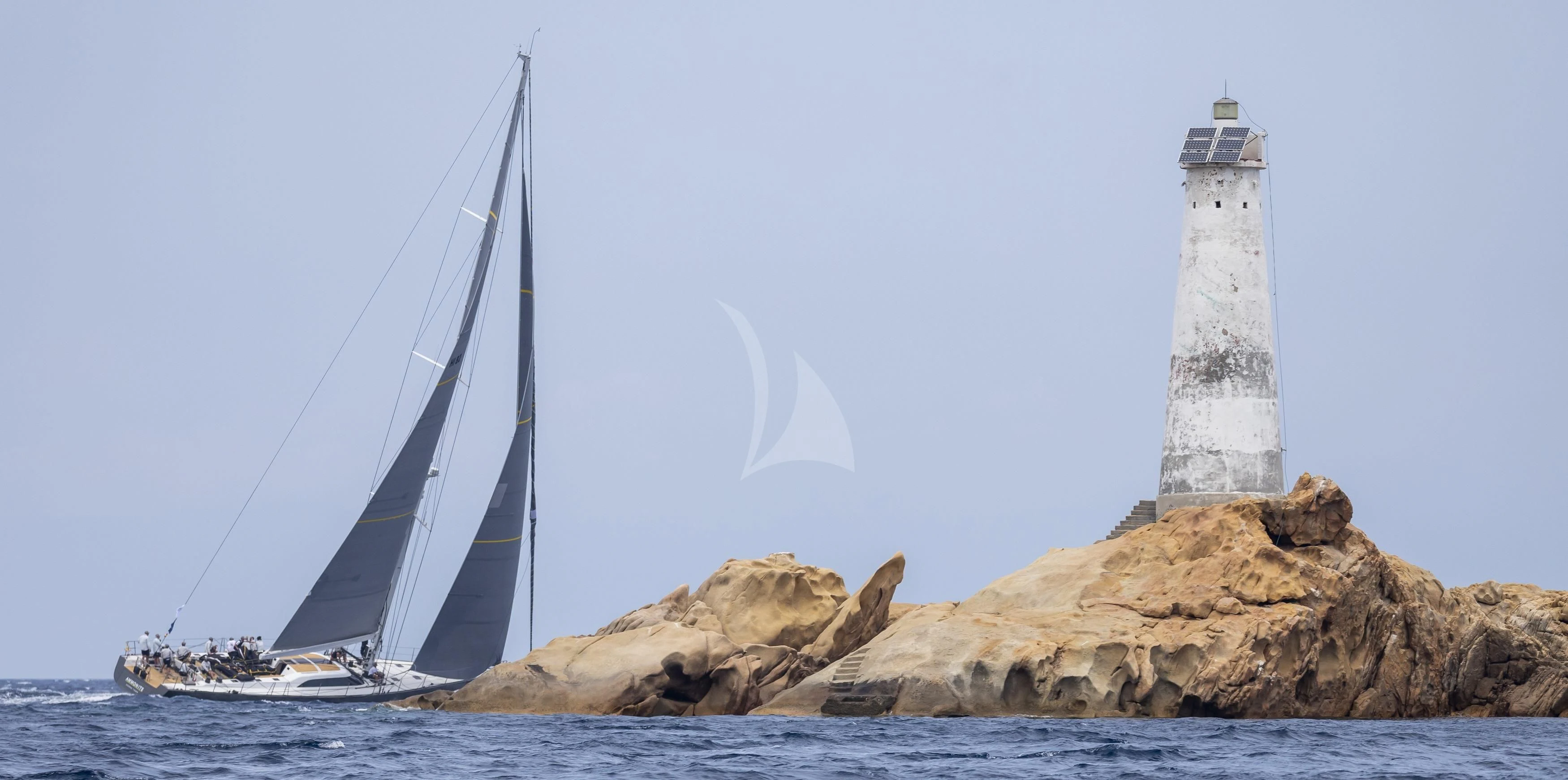 a lighthouse on a rock by the water aboard AMMONITE Yacht for Charter