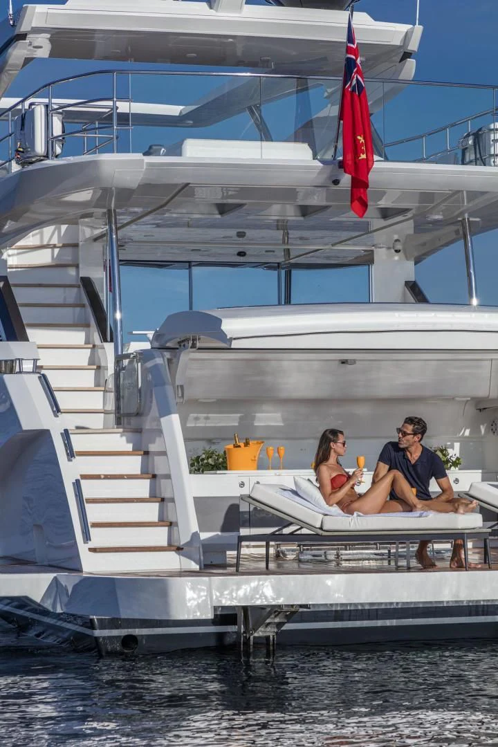 a man and woman sitting on a boat with a flag on the deck aboard PEARL Yacht for Sale