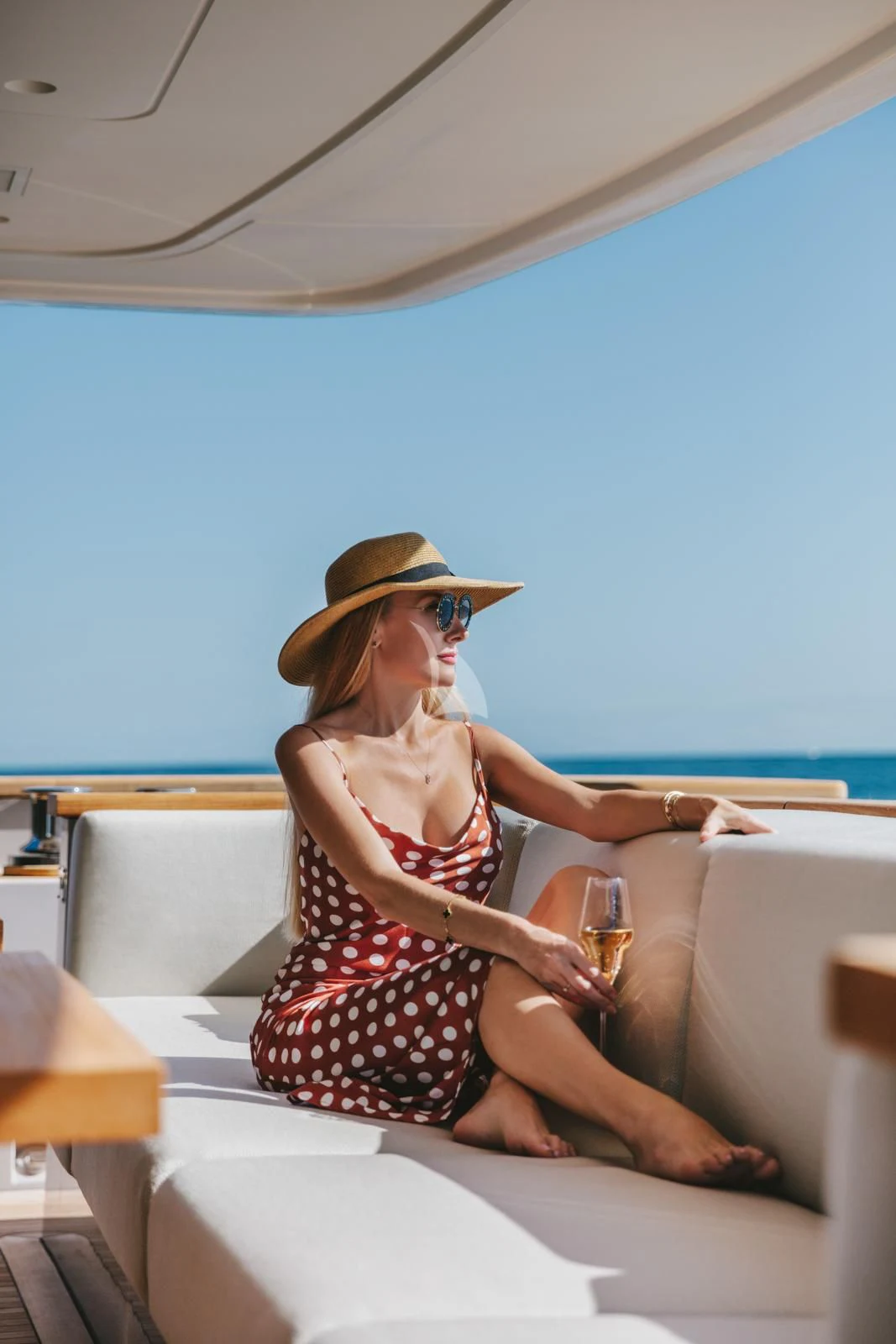 a woman sitting on a lounge chair with a glass of wine aboard PEARL Yacht for Sale