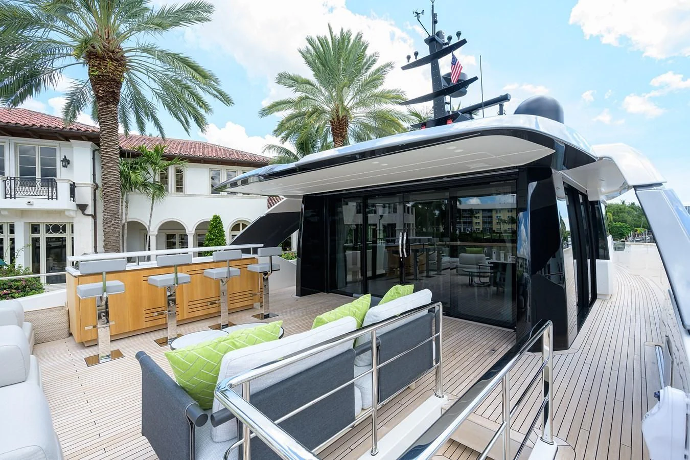 a deck with a pool and a building with palm trees and blue sky aboard PEARL Yacht for Sale