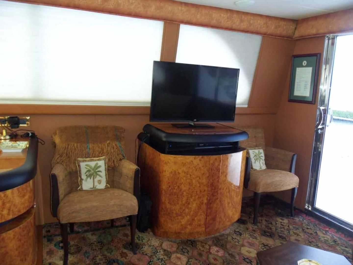 a tv on a stand in a room with chairs and a table aboard OHANA Yacht for Sale