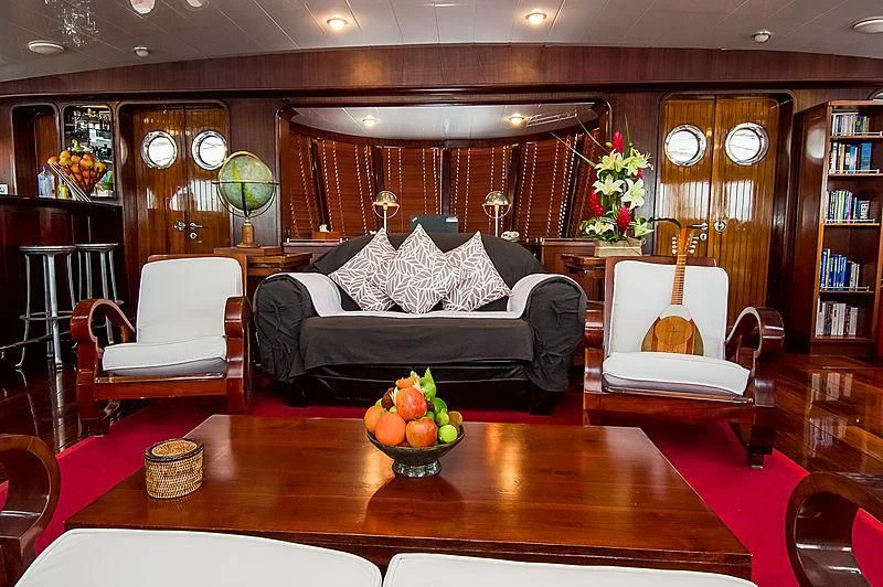 a living room with a black couch and a table with a vase of fruit on it aboard DOUCE FRANCE Yacht for Sale