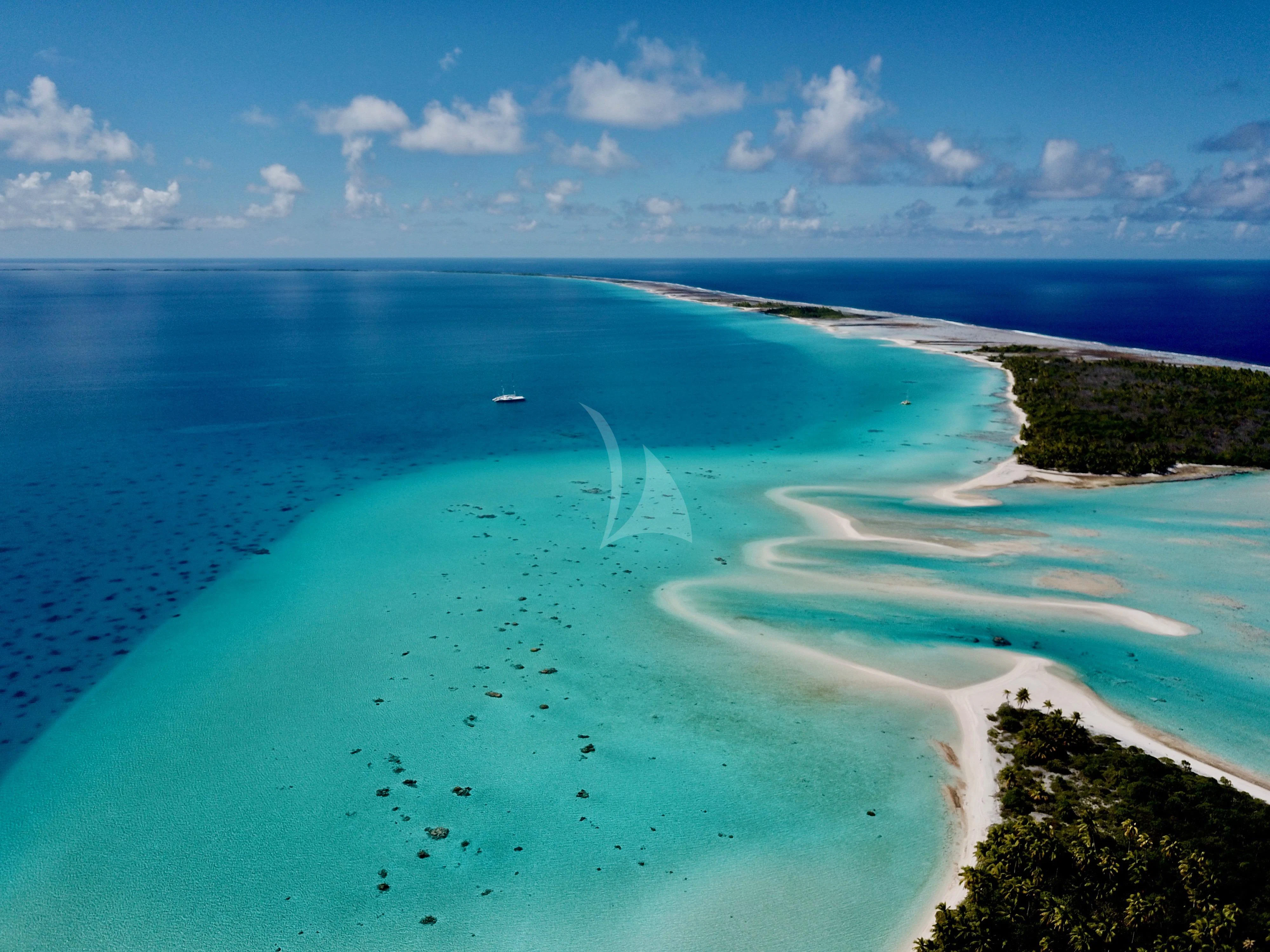 a beach with turquoise water and white sand aboard DOUCE FRANCE Yacht for Sale