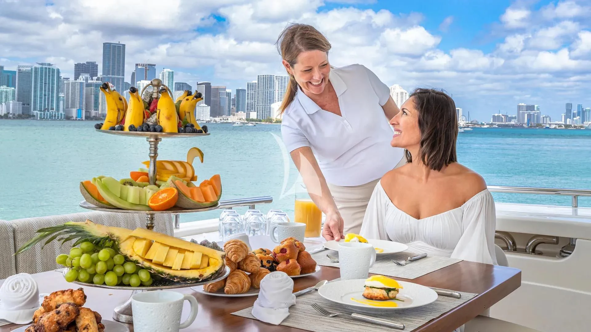 a man and woman eating at a table with food and water in the background aboard HOYA SAXA Yacht for Sale