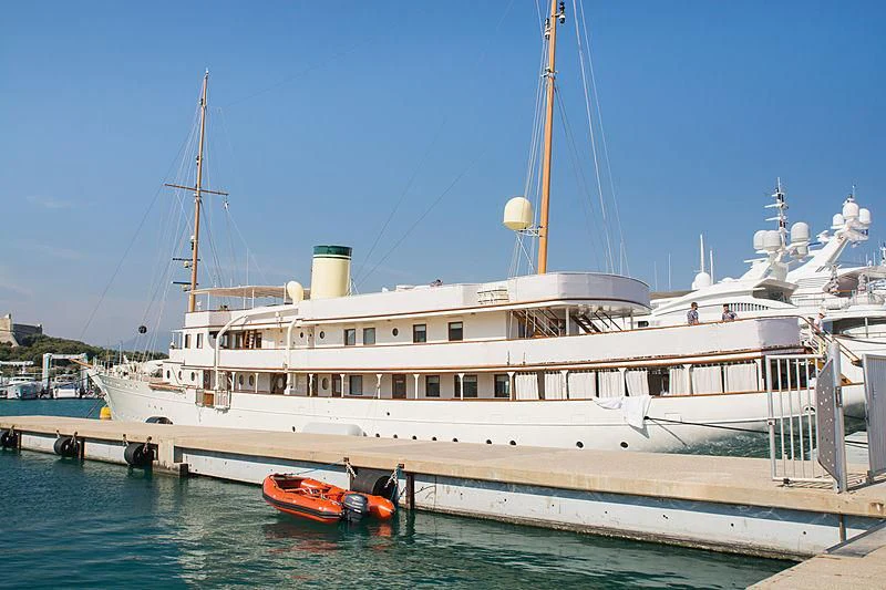 a large white boat with a red boat on the water aboard HAIDA 1929 Yacht for Sale