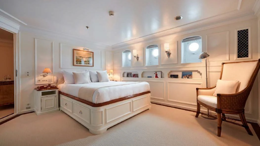 a bedroom with a bed and a chair aboard HAIDA 1929 Yacht for Sale