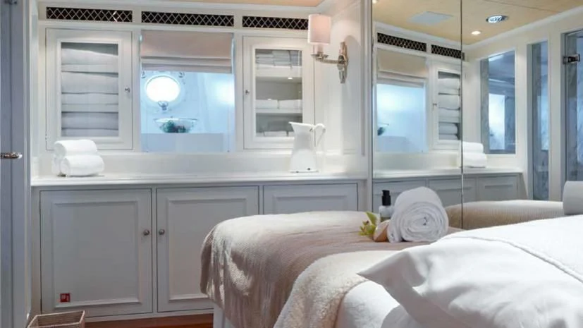 a white bedroom with a large white bed and a white cupboard aboard HAIDA 1929 Yacht for Sale