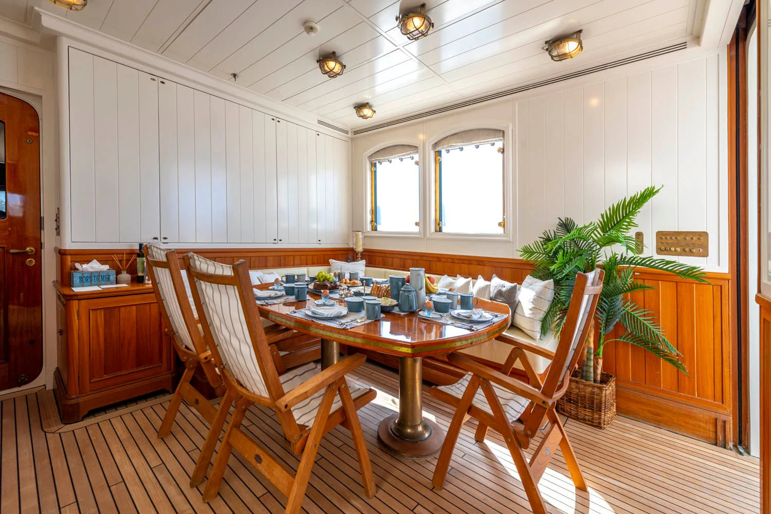 a dining table and chairs in a room with a plant on the table aboard STEEL Yacht for Sale
