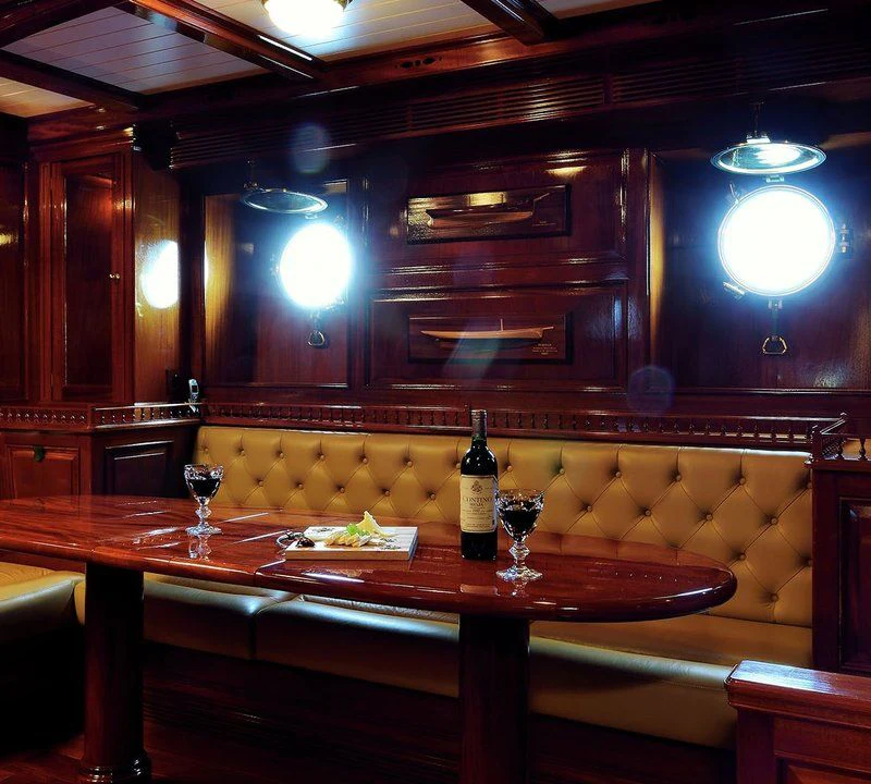 a bar with a table and wine bottle aboard STEEL Yacht for Sale