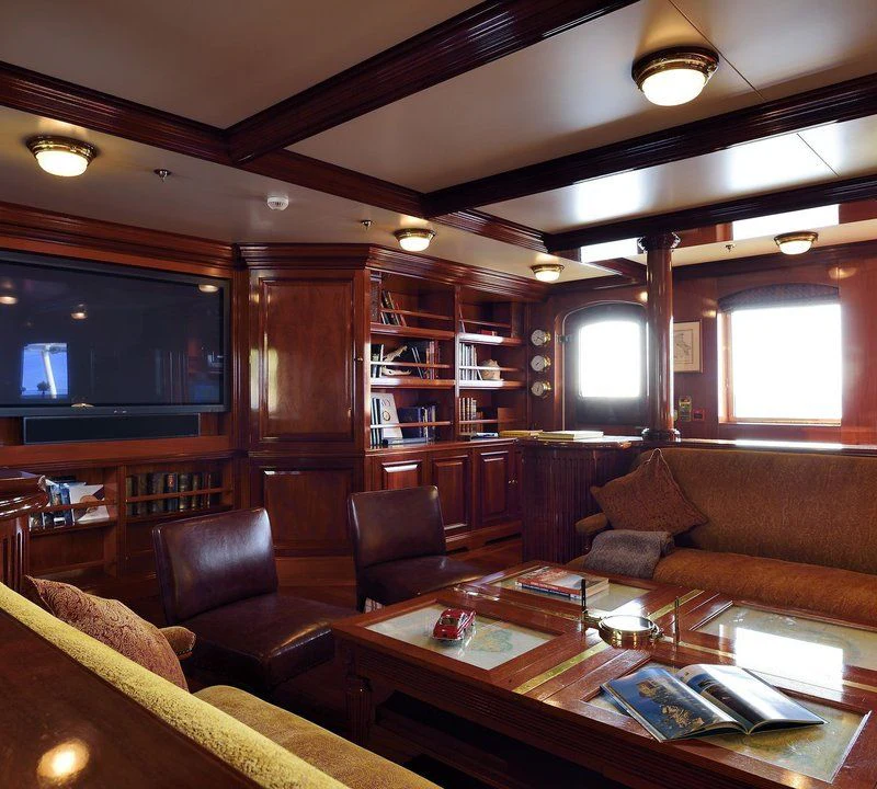 a living room with leather couches and a tv aboard STEEL Yacht for Sale