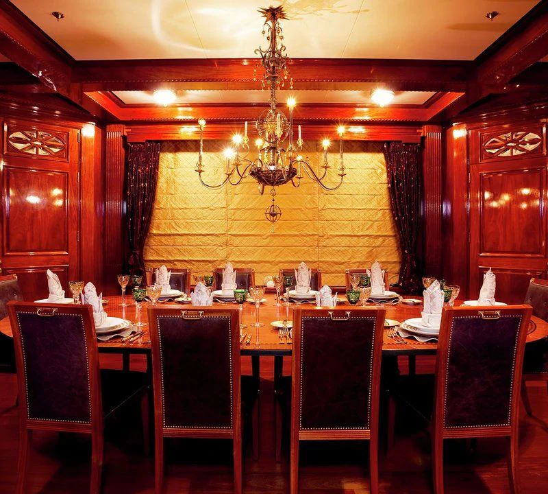 a dining room table with a chandelier above it aboard STEEL Yacht for Sale