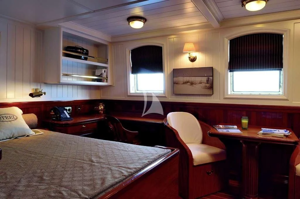 a bedroom with a bed and desk aboard STEEL Yacht for Sale