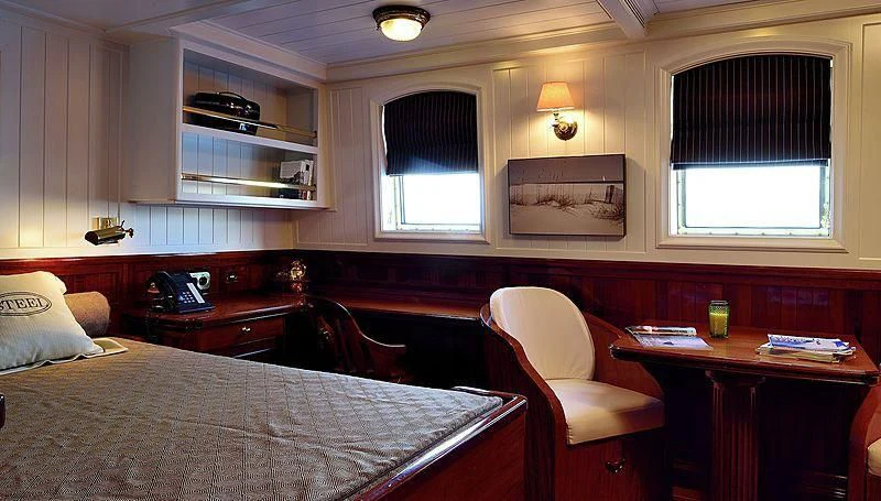 a bedroom with a bed and a chair aboard STEEL Yacht for Sale