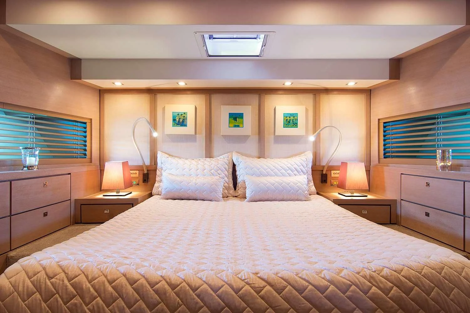 a bed with a white comforter and pillows in a room with a window and a mirror aboard SUN ANEMOS Yacht for Charter