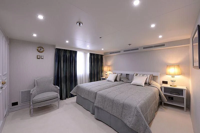 a bedroom with a bed and a chair aboard LADY SARYA Yacht for Sale