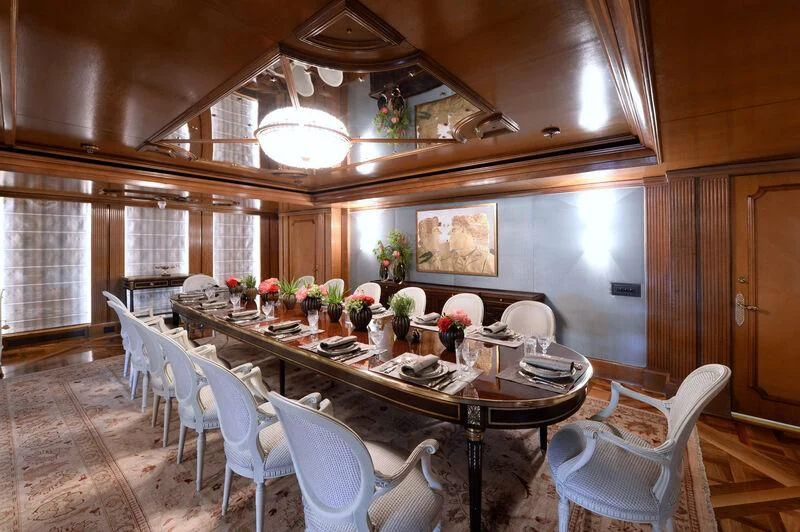 a large dining table in a large room with white chairs and a large window aboard LADY SARYA Yacht for Sale