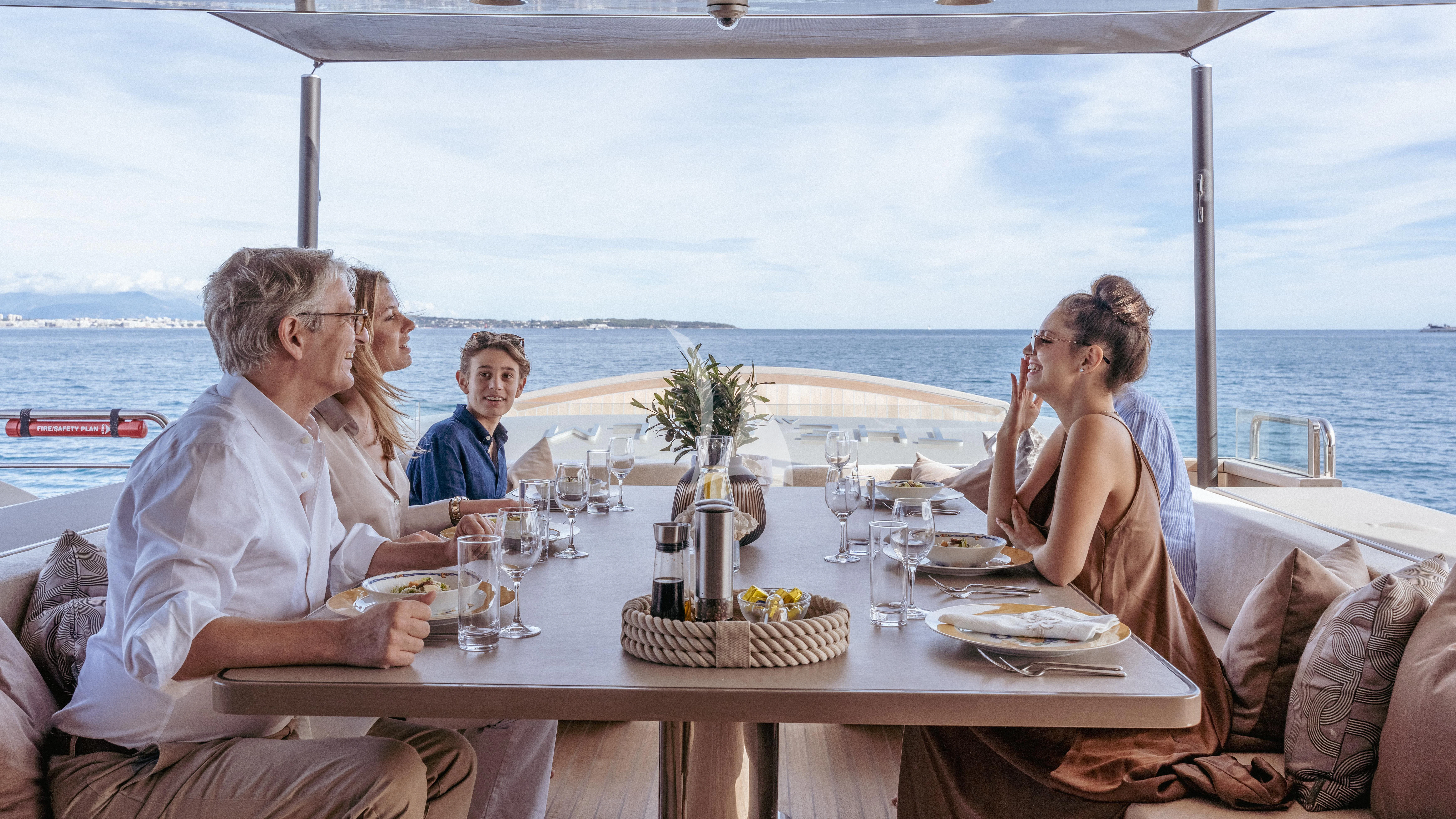 a group of people sitting around a table with food on it aboard THE PALM Yacht for Sale