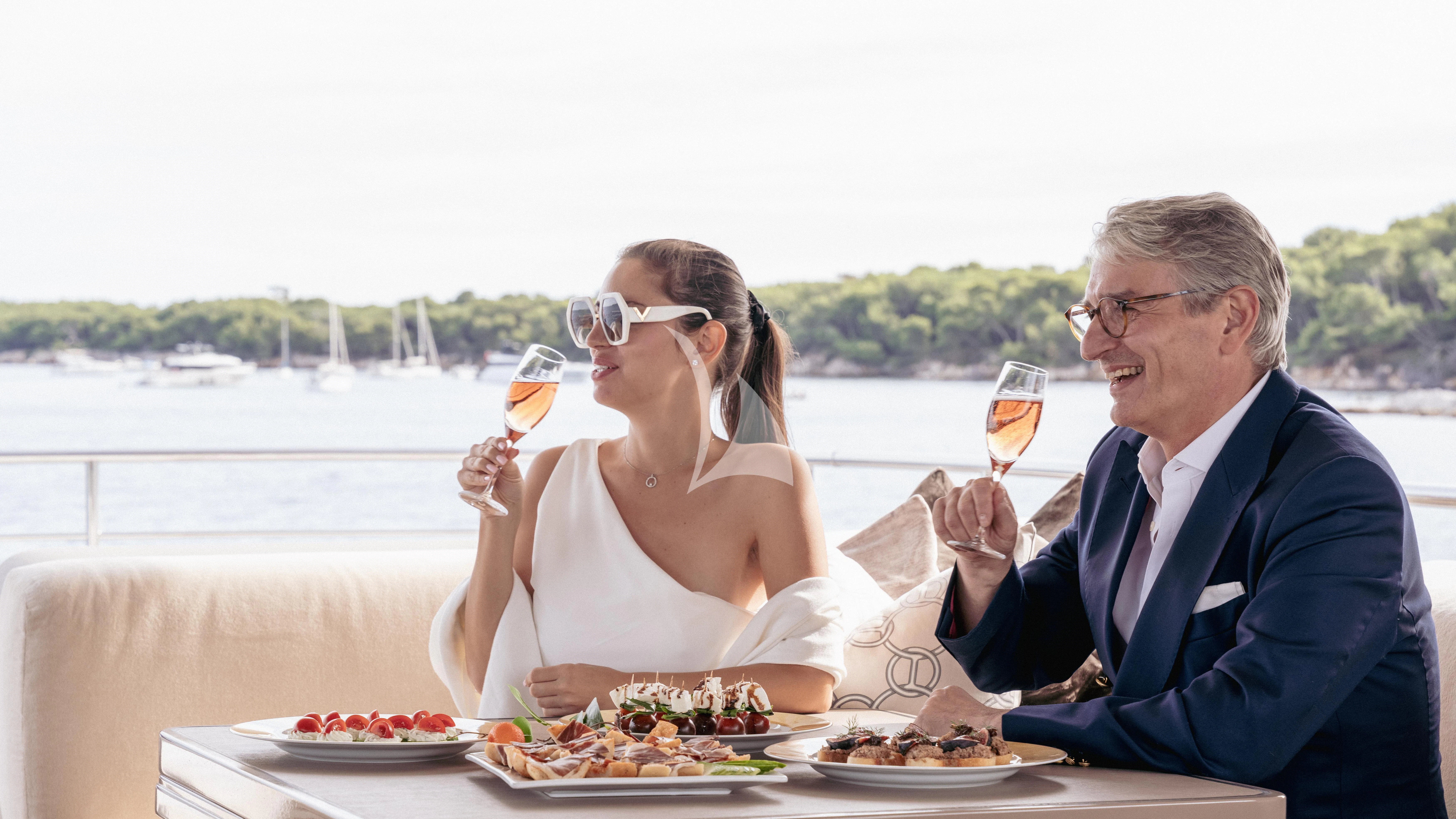 a man and woman eating at a table with food and wine aboard THE PALM Yacht for Sale