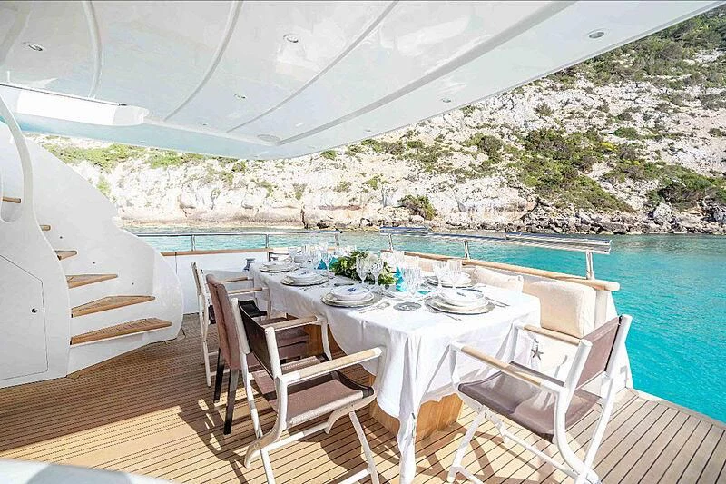 a table set for a meal on a deck overlooking a body of water aboard LEX Yacht for Sale