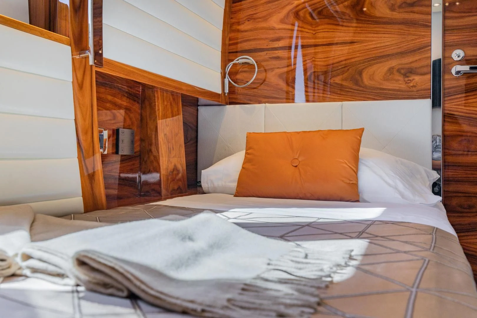 a bed with a white sheet and orange pillow aboard HATT MILL Yacht for Sale