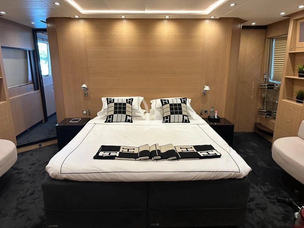a bed with white sheets and pillows aboard YCM 120 Yacht for Charter