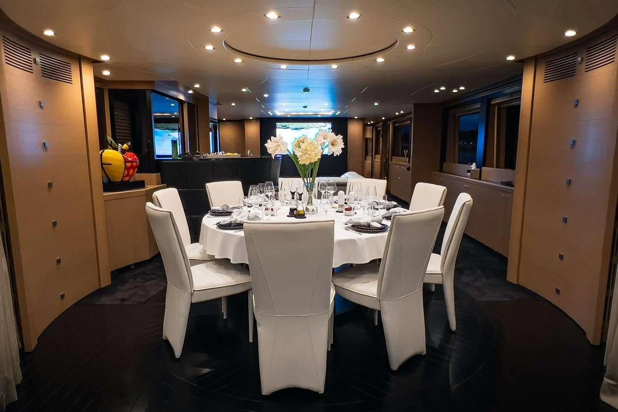 a dining room with white chairs aboard YCM 120 Yacht for Charter
