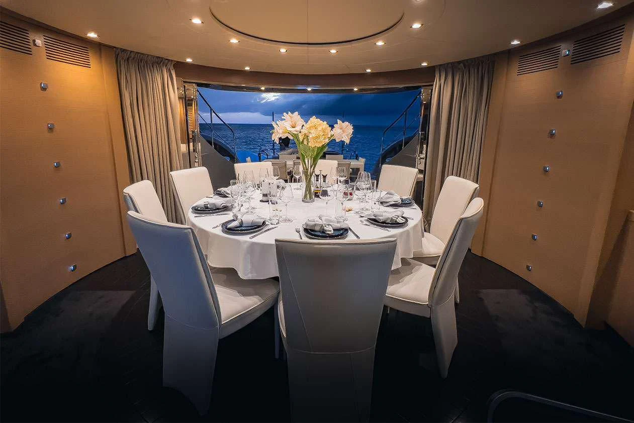 a dining room table with white chairs aboard YCM 120 Yacht for Charter