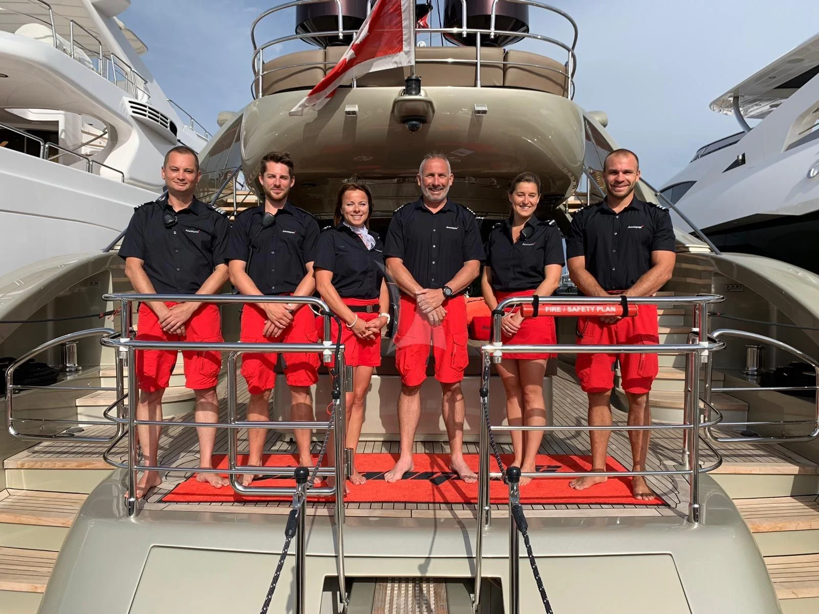 a group of people posing for a photo in front of a helicopter aboard YCM 120 Yacht for Charter