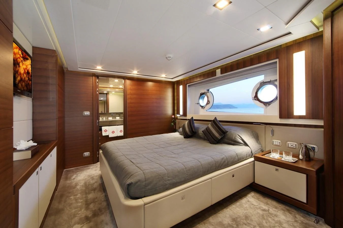 a bedroom with a bed and a wood cabinet aboard VELA Yacht for Sale