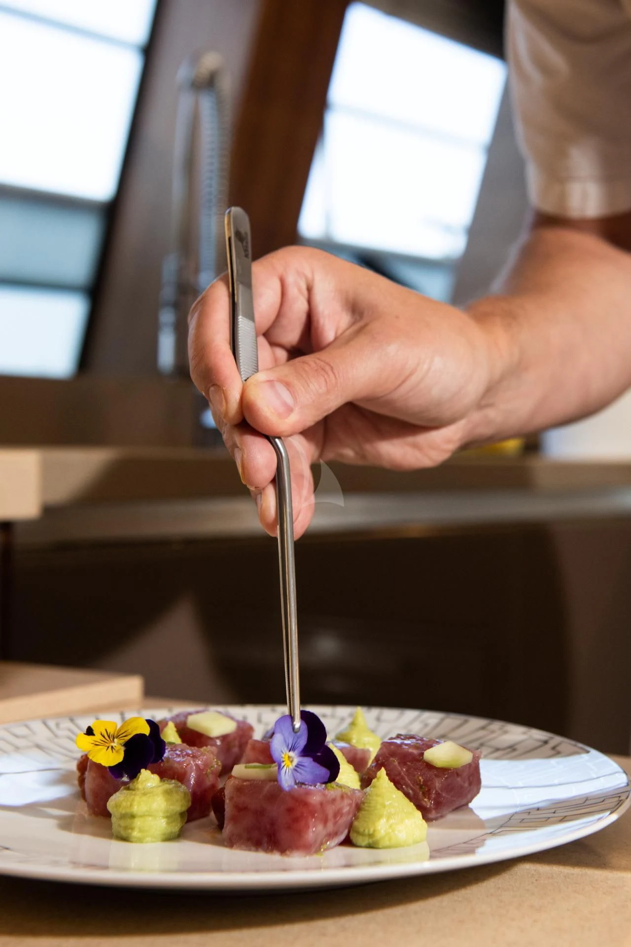 a person holding a knife to a plate of food aboard VELA Yacht for Sale