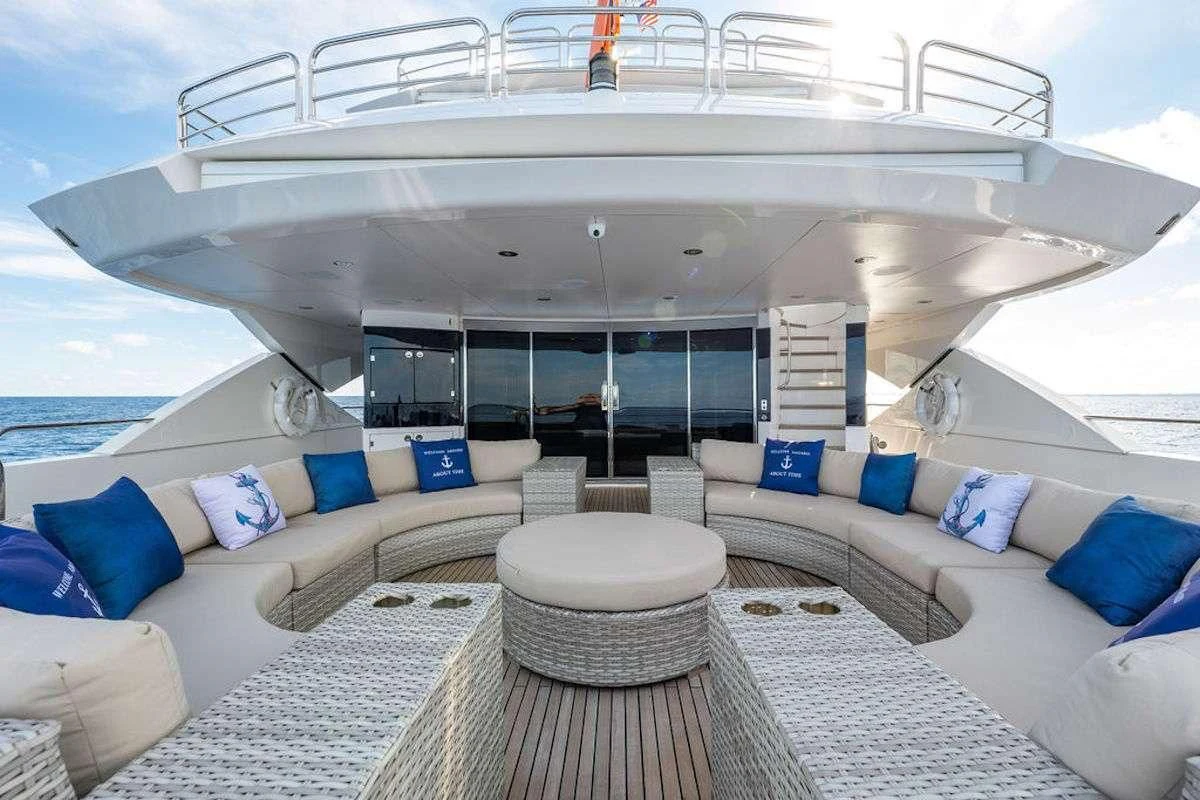 a large white yacht with a large white lounge chair and a large white sofa and blue pillows on aboard ABOUT TIME Yacht for Sale