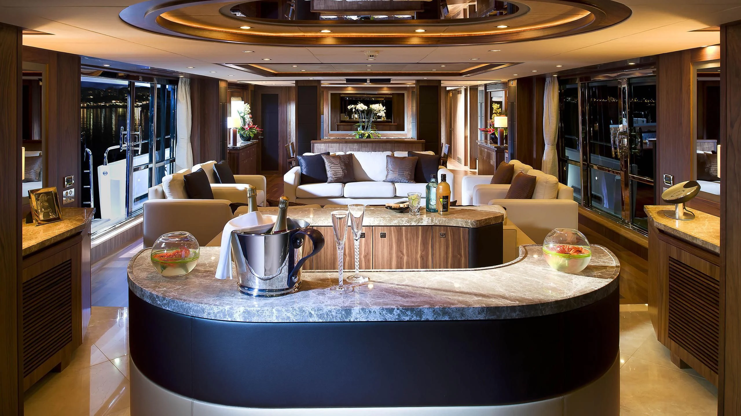 a large living room with a large round table and a large glass window aboard ABOUT TIME Yacht for Sale