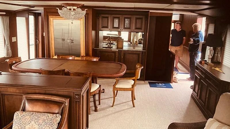 a room with a table chairs and a couple of men standing in the background aboard VICTORY Yacht for Sale