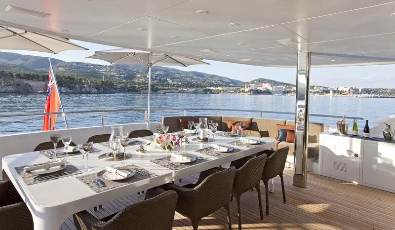 a table set for a meal on a deck overlooking a large body of water aboard JEMS Yacht for Sale