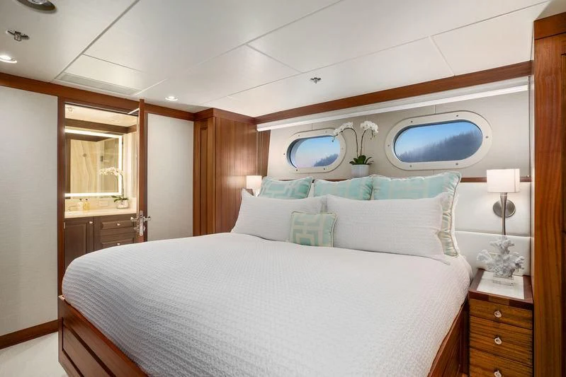 a bed with a white sheet and a blue window aboard ENDLESS SUMMER Yacht for Sale