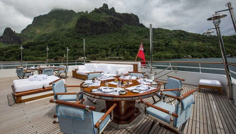 a deck with tables and chairs on it and a flag on the side aboard GRAND OCEAN Yacht for Sale