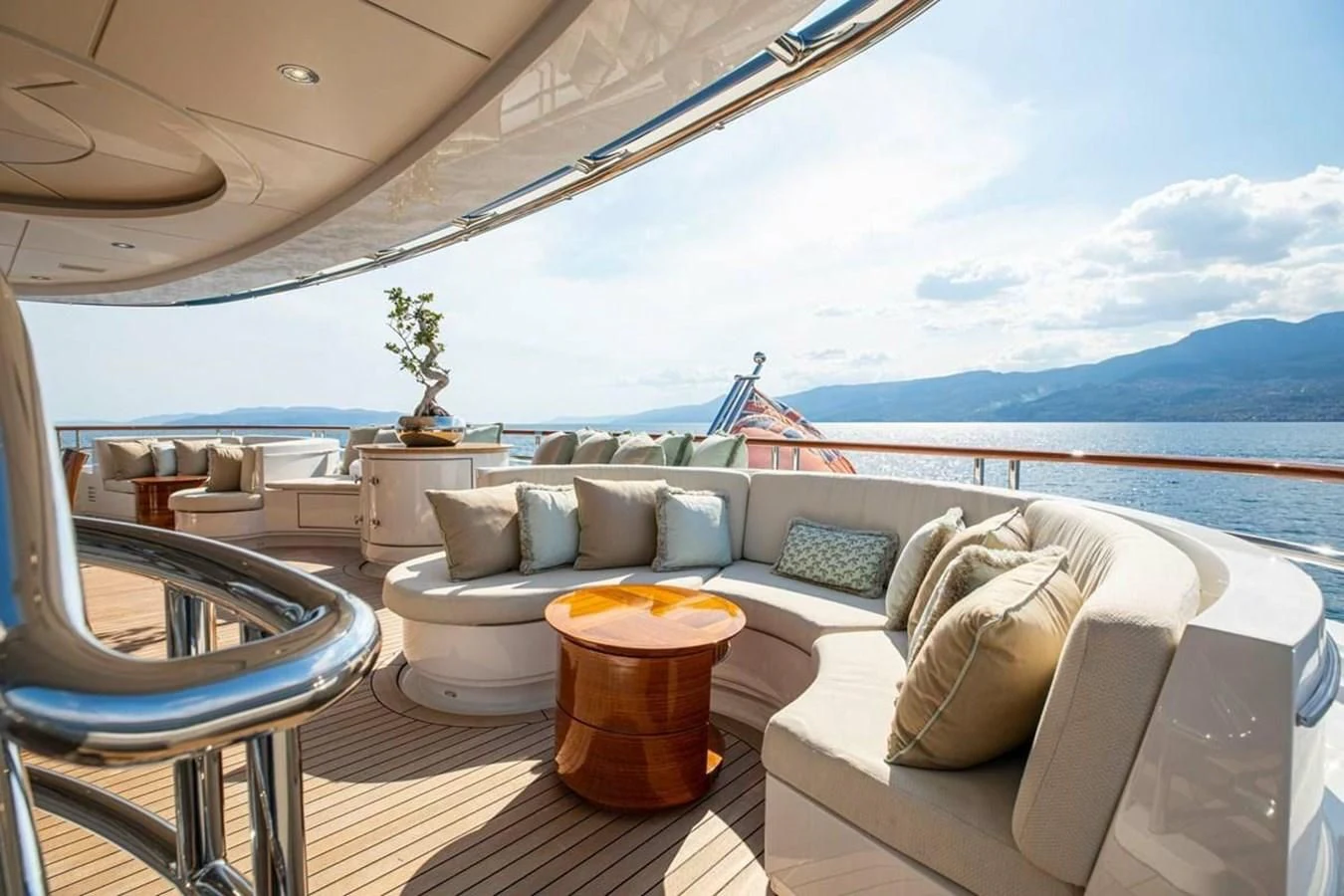 a large living room with a large body of water and mountains in the background aboard LUDZIE Yacht for Sale