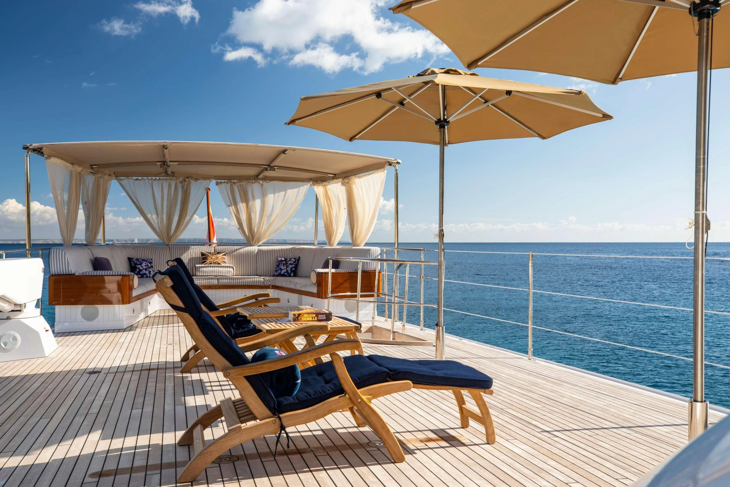 a couple of lounge chairs under an umbrella on a deck aboard ODYSSEY III Yacht for Sale
